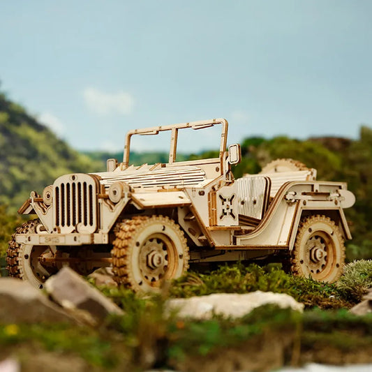 Wojskowy Jeep ROKR MC701 Army Field Car – gotowy model na skałach w terenie z zielonymi wzgórzami w tle, widok z boku lewego