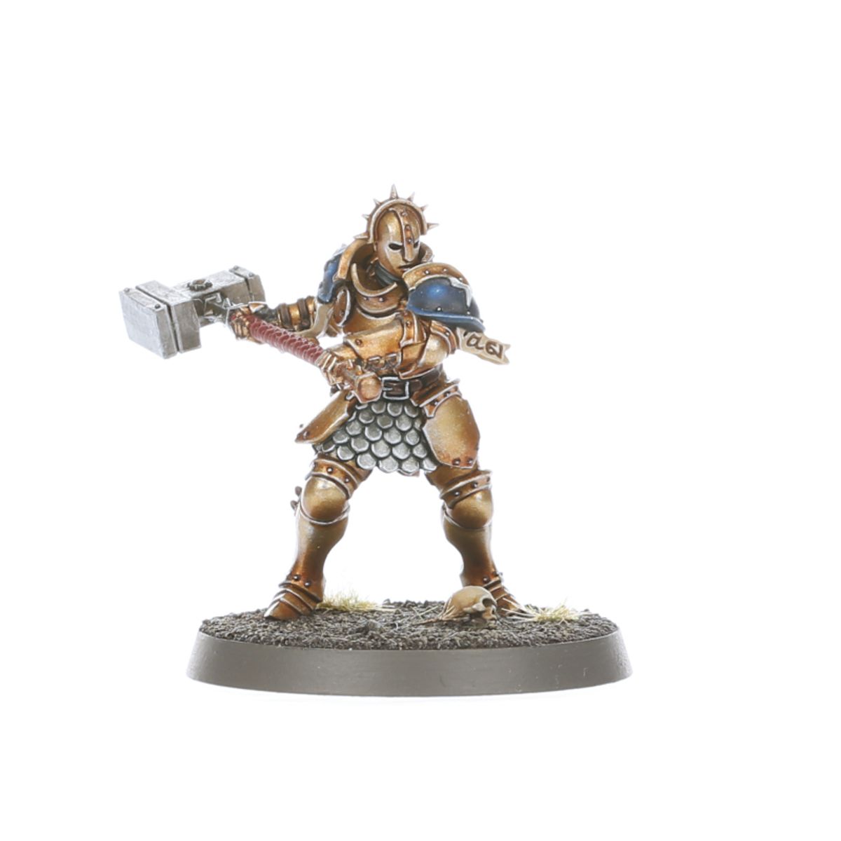  Liberator bez hełmu z kolczastym naramiennikiem - Stormcast Eternal w złoto-brązowej zbroi z niebieskim naramiennikiem, zamach warhammera w prawo, czaszka u stóp na podstawce - Warhammer Age of Sigmar