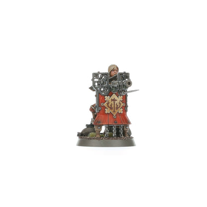 Freeguild Fusilier szeregowy - kobieta-żołnierz Cities of Sigmar z blond włosami w czerwonym płaszczu, kuca za masywną czerwoną pavise tarczą ze złotym symbolem, fusil-cannon z bagnetem gotowy do strzału - Warhammer Age of Sigmar