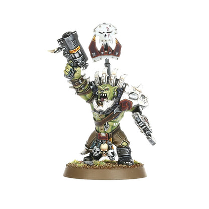 Ork Beast Snagga Nob - widok z przodu zielona skóra biała metalowa zbroja z kolcami i czerwonymi detalami szary thump gun cylindryczny z żółtymi ostrzeżeniami uniesiony w prawej ręce biała metalowa tarcza z czaszką i złotym klejnotem na kiju w lewej ręce brązowe spodnie z czaszkami przy pasie brązowa okrągła podstawka z trawą Orks Warhammer 40000
