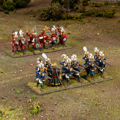 Warlord Games Ottoman Janissaries Regiment – diorama na stole: podstawka szermierzy w czerwonych mundurach i podstawka strzelców w niebieskich mundurach na trawiastym terenie 28mm Pike & Shotte