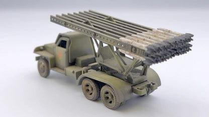Rubicon Models 280036 BM-13N Katiusza – zmontowany i pomalowany model plastikowy 1/56 28mm widok z boku-tyłu: Studebaker US6 6x6 w oliwkowej zieleni z czerwoną gwiazdą na drzwiach, wyrzutnia rakiet M-13 uniesiona pod kątem z rakietami na szynach, koła terenowe 6x6, białe tło, Bolt Action