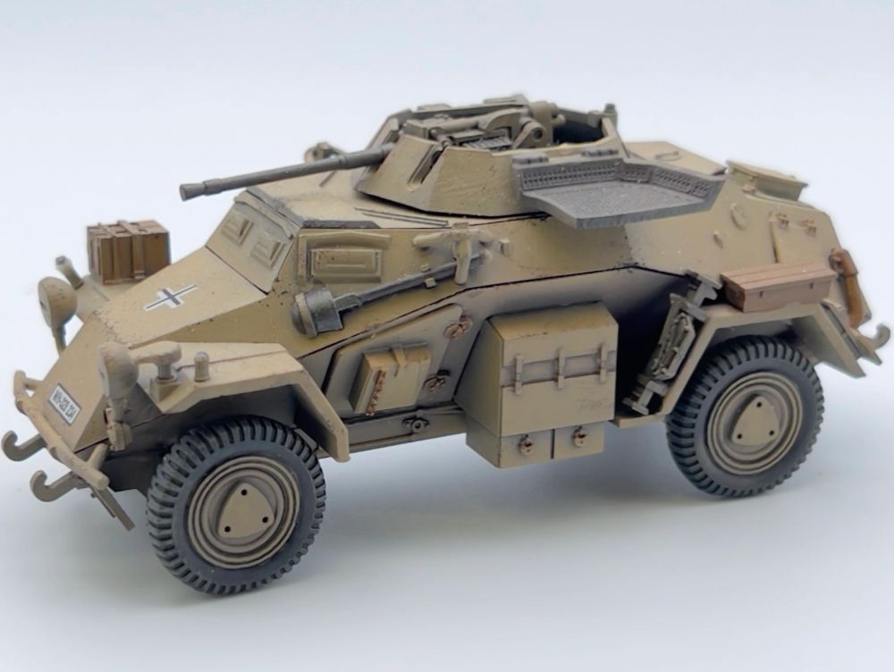 Rubicon Models 280062 SdKfz 222 – zmontowany i pomalowany model plastikowy 1/56 28mm widok z tyłu-boku: lekki samochód pancerny w pustynnym kamuflażu piaskowym DAK z krzyżem żelaznym na kadłubie, działko 20mm KwK 30 w otwartej wieży, siatka przeciwgranatowa otwarta, wyposażenie na kadłubie, koła terenowe, białe tło, Bolt Action