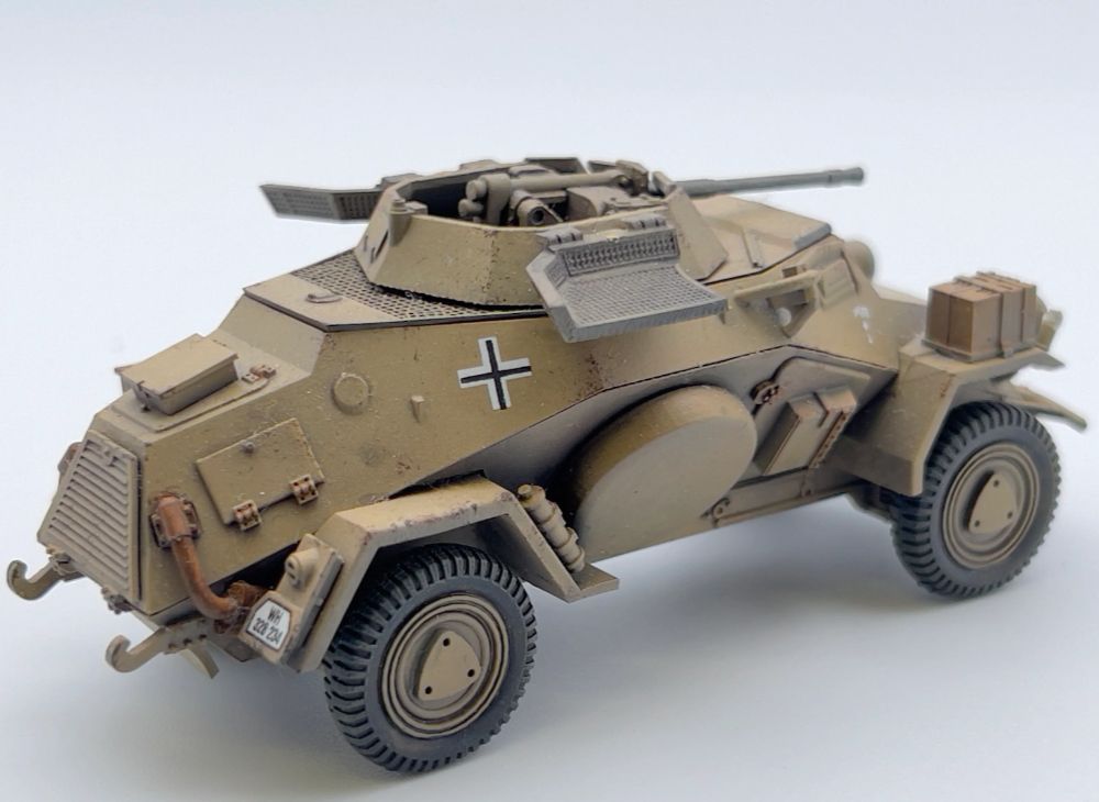 Rubicon Models 280062 SdKfz 222 – zmontowany i pomalowany model plastikowy 1/56 28mm widok z boku: lekki samochód pancerny w pustynnym kamuflażu piaskowym DAK z krzyżem żelaznym i numerem rejestracyjnym na kadłubie, działko 20mm KwK 30 w otwartej wieży, siatka przeciwgranatowa zamknięta, koła terenowe, białe tło, Bolt Action