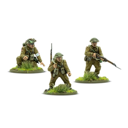 Warlord Games For King & Country – 3 figurki specjalistów 28mm od tyłu: żołnierz w berecie z karabinem Lee-Enfield i bagnetem (lewa), żołnierz w hełmie Brodie z karabinem Lee-Enfield (centrum), medyk klęczący w berecie z opaską Czerwonego Krzyża (prawa), detale plecaków i wyposażenia Bolt Action