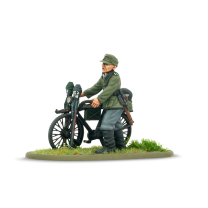 Warlord Games Early War German Infantry on Bicycles – zbliżenie figurki żołnierza Wehrmachtu w czapce polowej prowadzącego rower z wyposażeniem, detale malowania 28mm Bolt Action