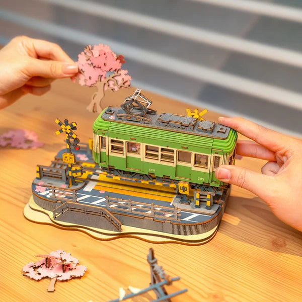Tramwaj Sakura Journey Rolife TGS02 – gotowy model w pudełku prezentowym z przezroczystą pokrywą i białą wstążką, trzymany w rękach