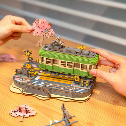 Tramwaj Sakura Journey Rolife TGS02 – gotowy model w pudełku prezentowym z przezroczystą pokrywą i białą wstążką, trzymany w rękach