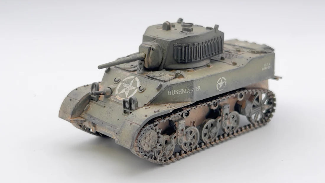 Rubicon Models 280023 M5A1 Stuart – zmontowany i pomalowany model plastikowy 1/56 28mm widok z boku-przodu: amerykański lekki czołg M5A1 Stuart w oliwkowej zieleni z białą gwiazdą i numerem USA 3013813 na kadłubie, armata 37mm M6, właz otwarty, gąsienice stalowe z weatheringiem, białe tło, Bolt Action