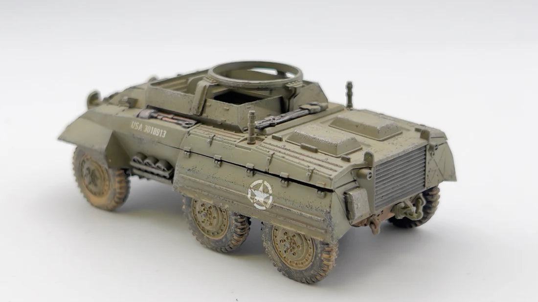 Rubicon Models 280028 M8 Greyhound – zmontowany i pomalowany model plastikowy 1/56 28mm widok z tyłu-boku: amerykański samochód pancerny w oliwkowej zieleni z numerem USA 3018913 na kadłubie, pierŜień MG na wieży, koła terenowe 6x6, białe tło, Bolt Action