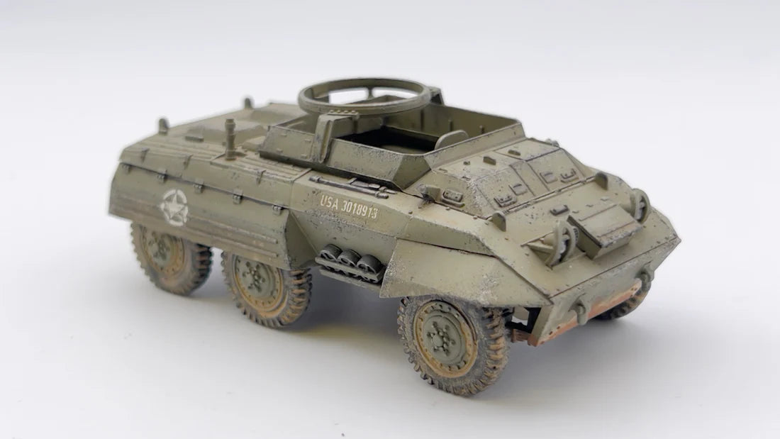 Rubicon Models 280028 M8 Greyhound – zmontowany i pomalowany model plastikowy 1/56 28mm widok z boku: amerykański samochód pancerny w oliwkowej zieleni z białą gwiazdą i numerem USA 3018913 na kadłubie, pierŜień MG na wieży, holuje przyczepę T3 w oliwkowej zieleni, koła terenowe 6x6, napis Steve Perry, białe tło, Bolt Action
