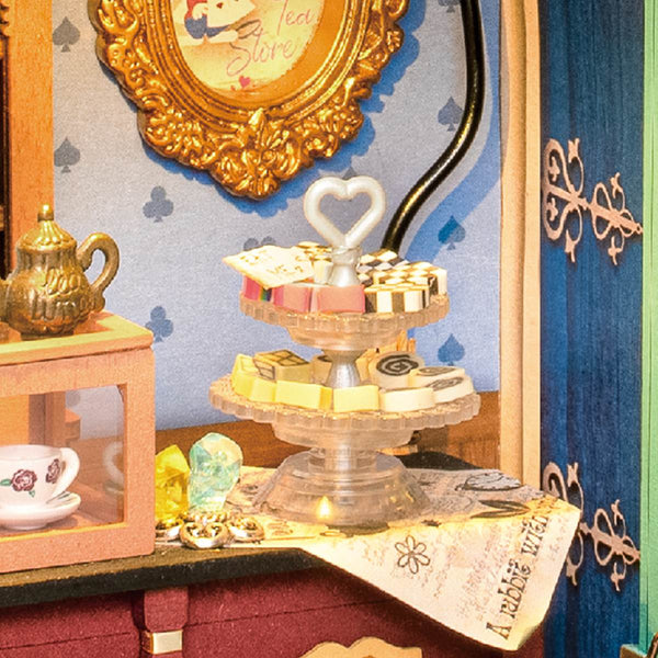 Herbaciarnia Alicji Alice's Tea Store Rolife DG156 – zbliżenie na trójpoziomowystand z ciastkami, złotą ramą i niebieską tapicerką w piki