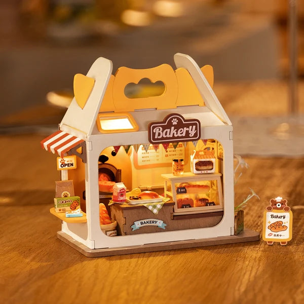 Piekarnia Teddy's Breadbox Rolife DS033 – gotowy model z włączonym LED obok różowego Strawberry Milk Box na stole z książkami