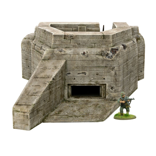 Flak Bunker 842010001 - pomalowany plastikowy bunker R677 28mm widok z przodu: beżowy betonowy bunker z poziomymi deskami szalunkowymi, prostokątne wejście czarne, schody po lewej stronie, zdejmowany dach na górze, ślady pocisków i zniszczenia, żołnierz niemiecki z karabinem dla skali - Bolt Action Warlord Games