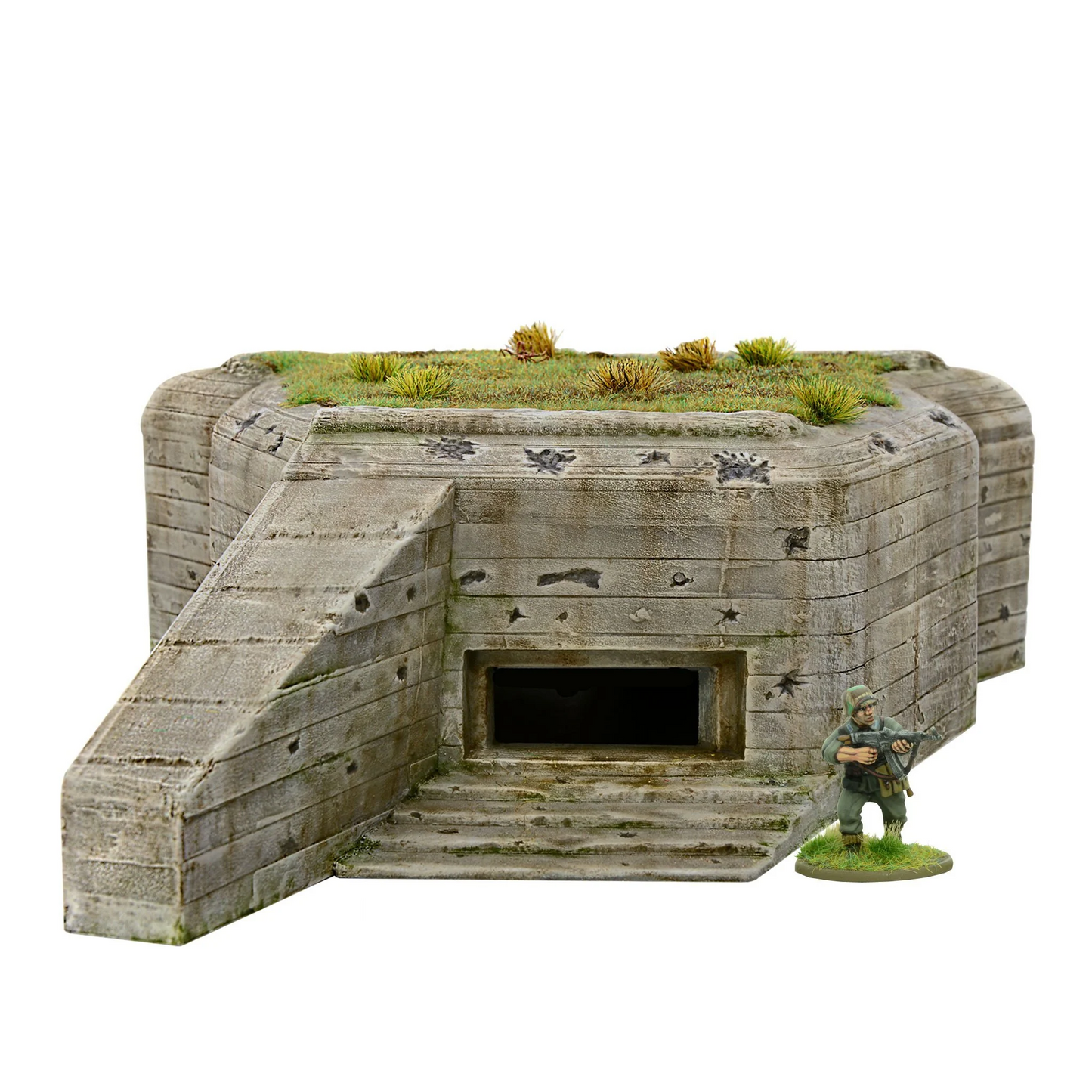 Coastal Defence Bunker 842010002 - pomalowany plastikowy bunker R612/R680 28mm: beżowy betonowy bunker z poziomymi deskami szalunkowymi, charakterystyczna ściana boczna flanking wall po lewej, prostokątne wejście czarne, zdejmowany dach na górze z zieloną trawą i tuftami, liczne ślady pocisków i zniszczenia, żołnierz niemiecki z karabinem dla skali - Bolt Action Warlord Games