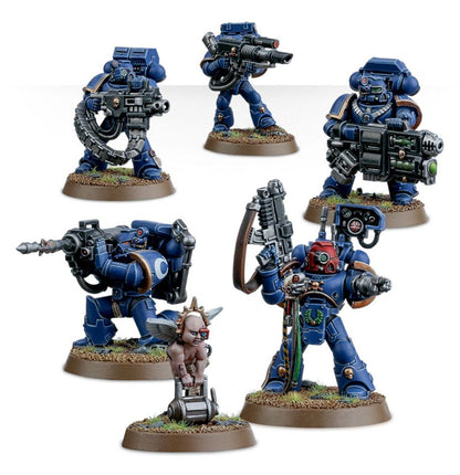 Devastator Squad Ultramarines - widok grupowy 5 modeli granatowa zbroja grav-cannon z łańcuchem i czaszką lascannon z czerwonym okiem multi melta z zielonym klejnotem Centurion z missile launcher w pozycji klęczącej Sergeant z czerwonym hełmem i zielonym wieńcem cherub z szarymi skrzydłami Space Marines Warhammer 40000