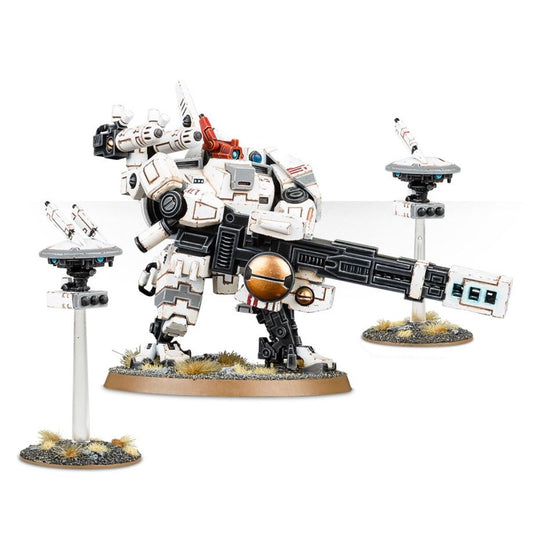 XV88 Broadside Battlesuit T'au Empire - widok z lewej biała zbroja z czarnymi detalami twin-linked rail rifle czarno-biała z miedzianą kulą energetyczną skierowana poziomo czerwony high yield missile system pod na lewym ramieniu czarny particle accelerator na plecach dwa drony na białych słupkach Shield Drone szary z niebieskimi sensorami i białymi rakietami Missile Drone szary z białymi rakietami brązowa owalna podstawka z trawą i żwirem T'au Warhammer 40000