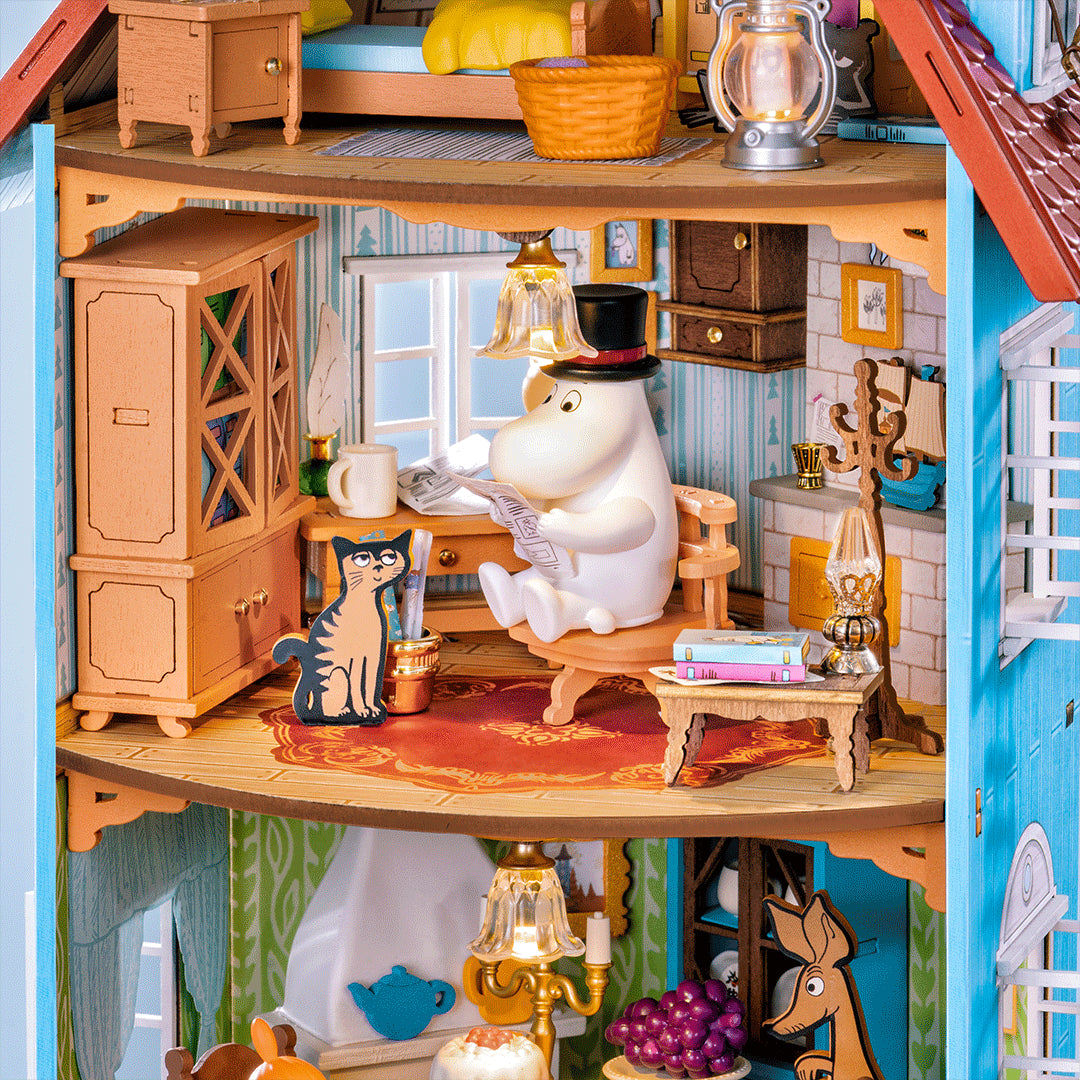 Dom Muminków Rolife DA009 Moominhouse – zbliżenie na stół jadalny z miniaturowym tortem, winogronami, miseczką i świecznikiem LED na żółtym obrusie