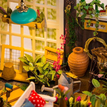 Kwiaciarnia Millera Miller's Flower House Rolife DG108 – zbliżenie na wnętrze z góry: koszyki z kwiatami, miniaturowe słoiki i kolorowe poduszki na ławce