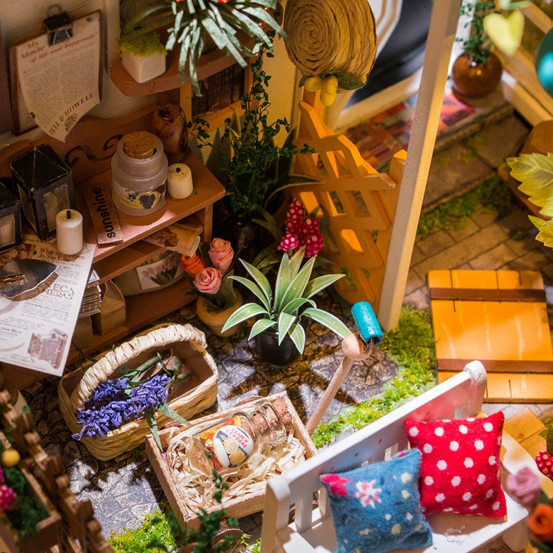 Kwiaciarnia Millera Miller's Flower House Rolife DG108 – zbliżenie na żelazne ogrodzenie z kolorowymi kwiatami i szufladą w tle