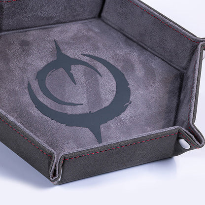 Malediction Premium Dice Tray – zbliżenie na szare logo Malediction wytłoczone na ciemnoszarej zamszowej powierzchni tacy z czerwonymi szwami na białym tle