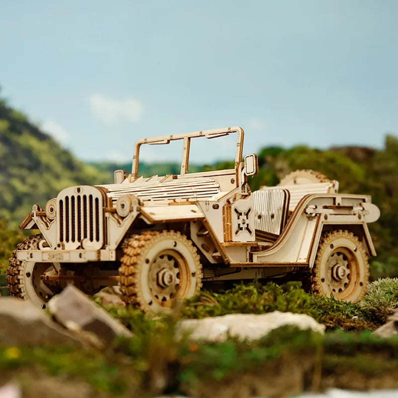 Wojskowy Jeep ROKR MC701 Army Field Car – gotowy model na skałach w terenie z zielonymi wzgórzami w tle, widok z boku lewego