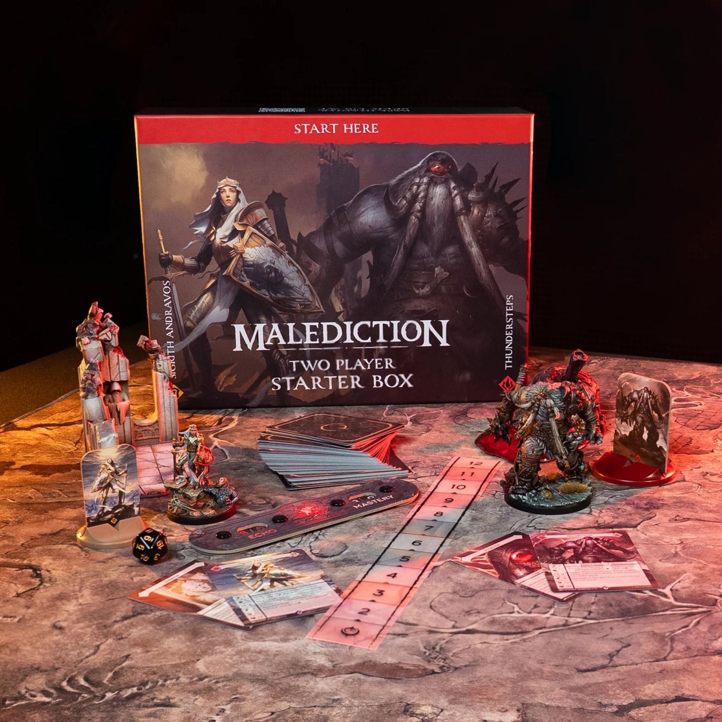 Malediction Two Player Starter Box Sigrith vs Thundersteps – pudełko gry z rozłożoną zawartością: standees Sigrith i Thundersteps, talia kart, linijka, pasek Echo/Mastery, kość D20 i karty jednostek na ciemnym kamiennym stole
