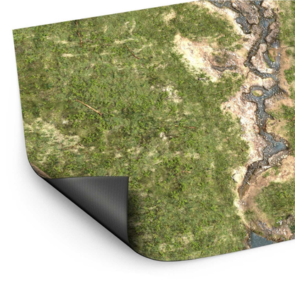 Wargame Mat Duskriver Meadows – mata neoprenowa 120x180cm zrolowana z widocznym spodem antypoślizgowym, zielona łąka z rzeką i kamieniami, białe tło