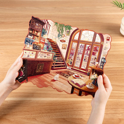 Przytulna Zimowa Kawiarnia Rowood TA006 Cozy Winter Café – ręce trzymające gotowe puzzle nad drewnianym stołem, widok z góry z widocznym białym kotem przy stoliku