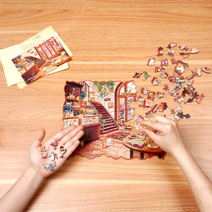 Przytulna Zimowa Kawiarnia Rowood TA006 Cozy Winter Café – ręce układające puzzle na drewnianym stole z rozrzuconymi elementami o unikalnych kształtach i naklejką referencyjną