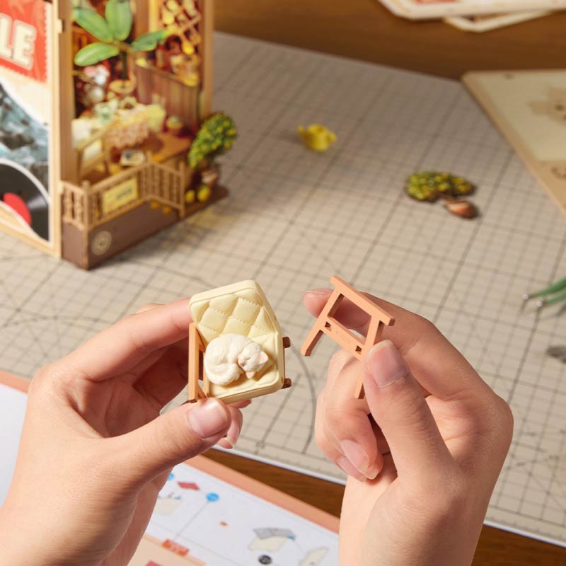 Sunset Isle Rolife TGB18 – book nook na półce z książkami, świecący ciepłym bursztynowym światłem w miniaturowej scenie kawiarni