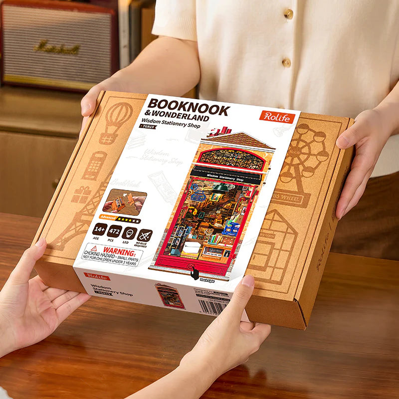 Sklep z Papeternią Wisdom Stationery Shop Rolife TGB19 – zbliżenie na ręce składające miniaturową szafkę z drewnianych elementów na stole z innymi częściami