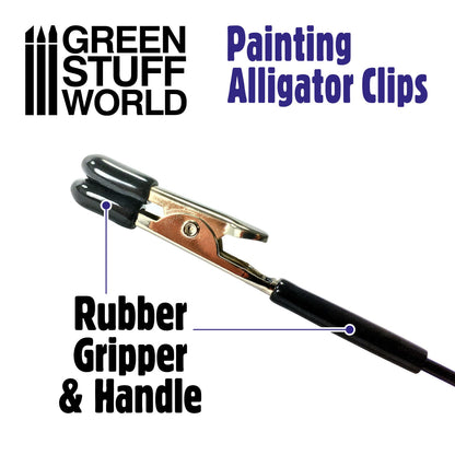 Alligator Clips Green Stuff World – zbliżenie na krokodylek malarski z czarną gumową osłoną szczęk (Rubber Gripper) i czarnym uchwytem (Handle), napis "Painting Alligator Clips", logo GSW
