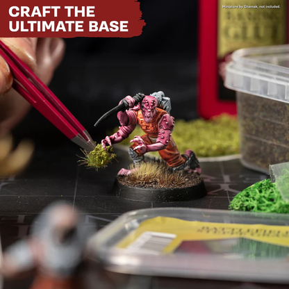 Battlefields Basing Set The Army Painter – modelarz umieszcza kępkę Summer Undergrowth na podstawce figurki tabletop pinsetą
