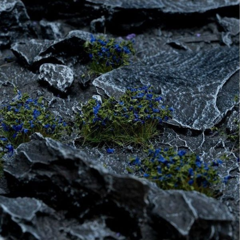 Blue Flowers 6mm Wild Gamers Grass - diorama z ciemnymi łupkowymi skałami pokryta niebiesko-fioletowymi kępkami kwiatowymi tworzącymi magiczny, mroczny klimat
