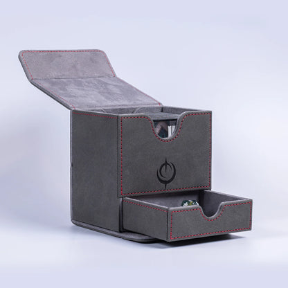 Malediction Premium Leather Deck Box – pudełko otwarte z uniesionym wieczkiem i wysuniętą dolną szufladą z zieloną kością D20, widoczna górna komora na karty z wycięciem, logo Malediction na boku, szare tło
