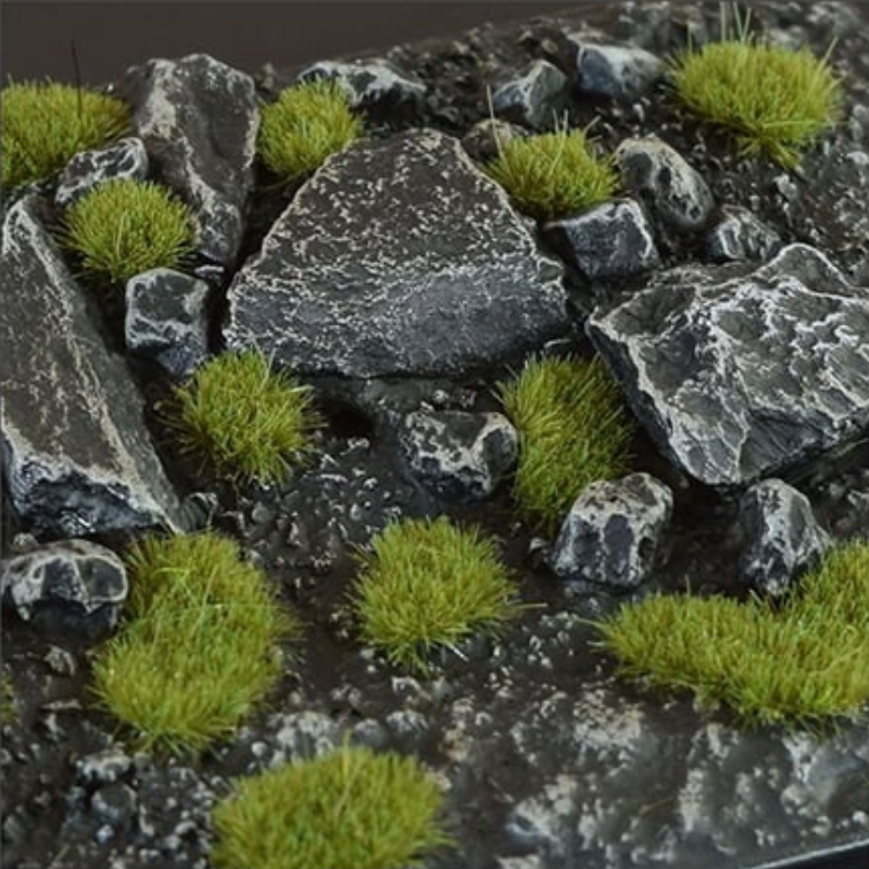 Dry Green Tufts 2mm Small Gamers Grass - diorama skalna z czarnymi łupkowymi kamieniami pokryta drobnymi zielonymi kępkami trawy tworzącymi realistyczny, naturalny teren
