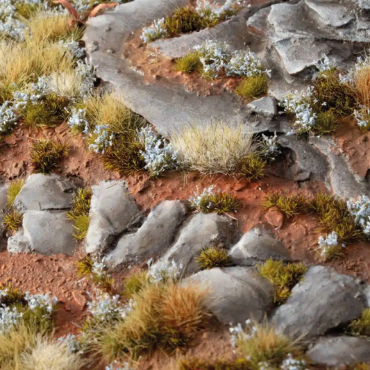 Forget-Me-Not Tiny Flowers 4mm Gamers Grass - diorama skalna z czerwoną ziemią i kamieniami pokryta drobnymi niebieskimi kępkami niezapominajek wśród traw
