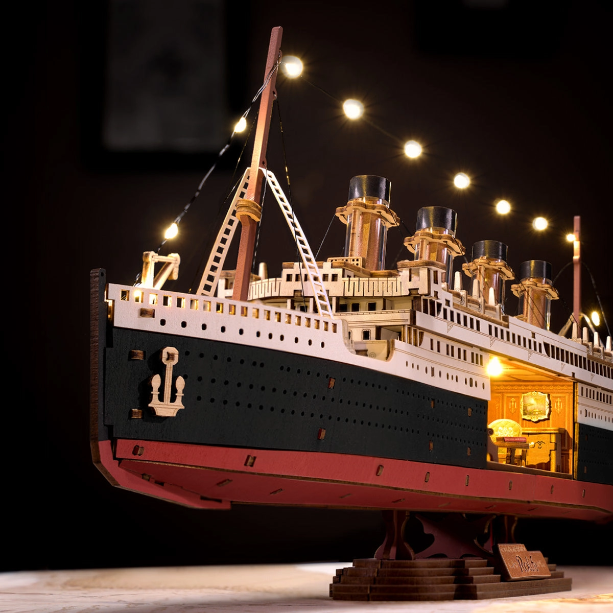 Drewniany puzzle 3D 1912 Eternal Atlantic Voyager Rolife TGL02 – ukończony model podświetlony LED na czarnym tle: cztery miedziane kominy, światła na olinowaniu i podświetlone wnętrze
