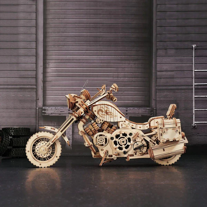 Mechaniczny drewniany model 3D Motocykl Cruiser Rolife RK026e – ukończony model na tle garażu z metalową bramą, widok z lewej strony
