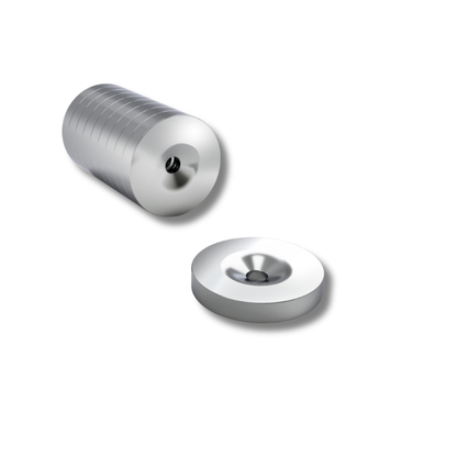 Green Stuff World 12595 – magnesy neodymowe 15x2,5mm z otworem, stos krążków i pojedynczy magnes na białym tle

