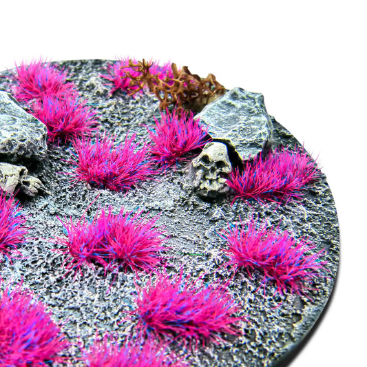 Martian Fluor Tufts 6mm Andromeda Pink Green Stuff World - zbliżenie na okrągłą podstawkę sci-fi z różowymi fluorescencyjnymi kępkami trawy, czaszką i kamieniami
