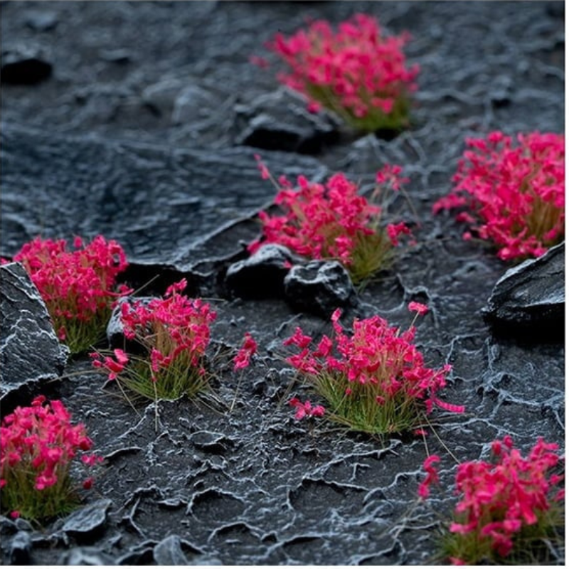 Pink Flowers 6mm Wild Gamers Grass - diorama z ciemnymi łupkowymi skałami pokryta intensywnie różowymi kępkami kwiatowymi tworzącymi uderzający kontrast kolorystyczny
