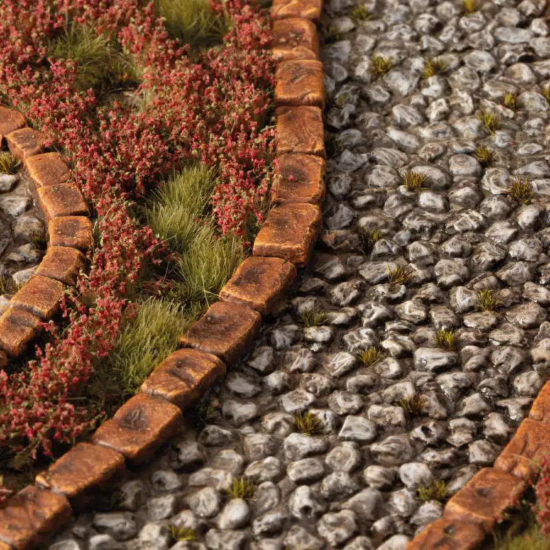 Red Camellia Flowers 6mm Gamers Grass - diorama z brukowanym placem i żwirkiem pokryta gęstymi czerwonymi kępkami kamelii przy ceglanych krawężnikach
