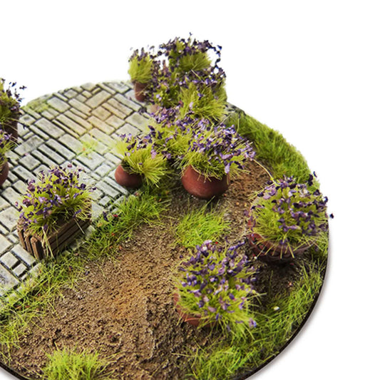 Shrub Tufts 6mm Dark Violet Green Stuff World - diorama z brukowaną ścieżką i krzewinkami z ciemnofioletowymi kwiatami na okrągłej podstawce z piaskiem i trawą
