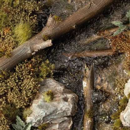 Swamp Shrubs 6mm Gamers Grass - diorama bagienna z mokrą ziemią, kamieniami i gałęziami pokryta brązowo-zielonymi kępkami krzewów bagiennych tworzącymi mroczny klimat mokradeł
