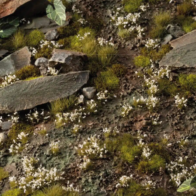 White Lily Tiny Flowers 4mm Gamers Grass - diorama skalna z kamieniami i mchem pokryta drobnymi białymi kępkami lilii wśród zielonej trawy
