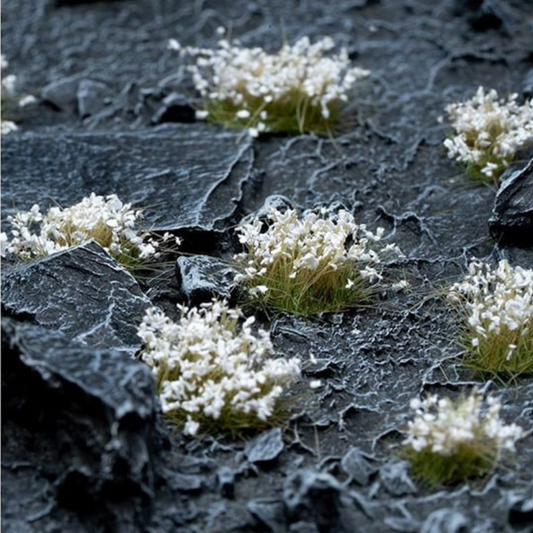 White Flowers 6mm Wild Gamers Grass - diorama z ciemnymi łupkowymi skałami pokryta śnieżnobiałymi kępkami kwiatowymi tworzącymi delikatny kontrast na czarnym tle

