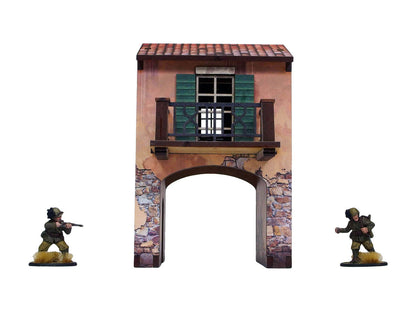 WW2 Italy Gate Balcony (1) PREPAINTED – brama uliczna z nadbudówką i balkonem, widok z przodu: łukowy przejazd bramny z kamiennym cokołem, balkon z drewnianą balustradą i zielonymi okiennicami, dwie figurki żołnierzy 28mm Bolt Action po bokach, białe tło
