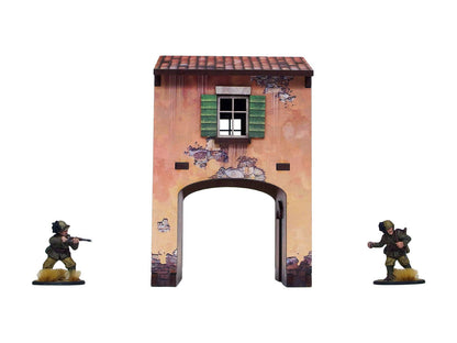 WW2 Italy Gate House (1) PREPAINTED – brama uliczna z nadbudówką, widok z przodu: łukowy przejazd bramny z wysokim otworem, postarzany tynk odsłaniający kamień, zielone okiennice na piętrze, dach z dachówek terakotowych, dwie figurki żołnierzy 28mm Bolt Action po bokach, białe tło

